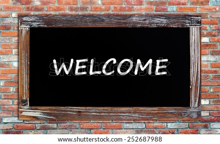 Welcome on vintage chalk board on brick wall background