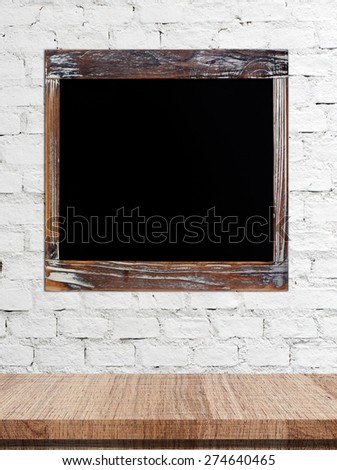Blank vintage chalk board  over table on white brick wall, grunge background