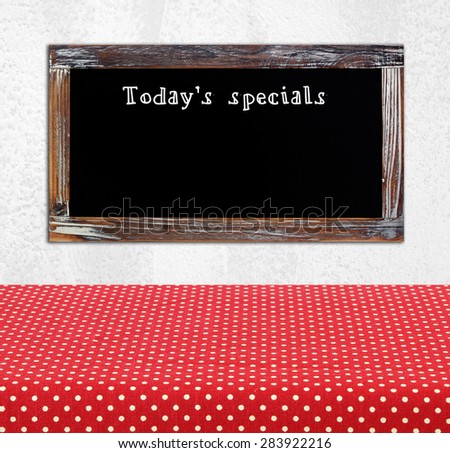 Today\'s special on vintage chalk board over cement wall and empty wood table background, food and drinks, food display montage