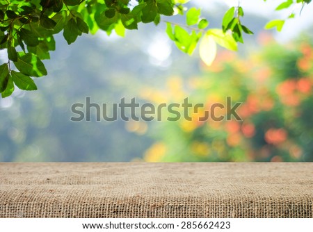 Empty table covered with sackcloth over blurred trees with bokeh background, product display template