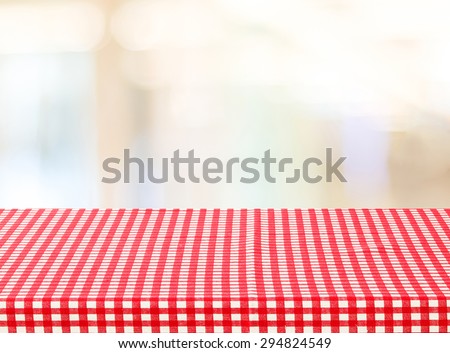 Empty table with red check tablecloth over blur festive bokeh background, product display