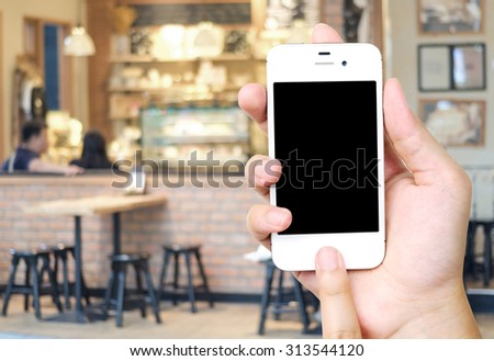 Hand holding smart phone over blur restaurant background, restaurant reservation, food online, food delivery concept