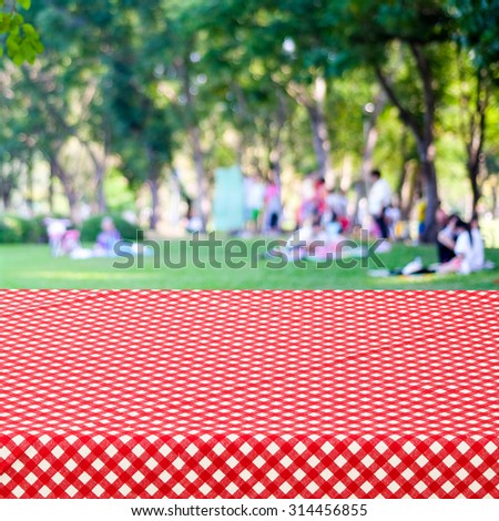 Empty table and red tablecloth with blur park with people background, for product display montage