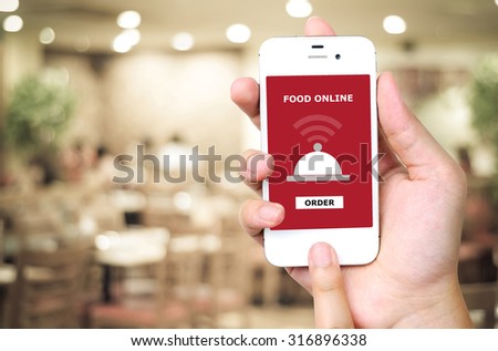 Hand holding smart phone with food online device on screen over blur restaurant background, food online, food delivery concept