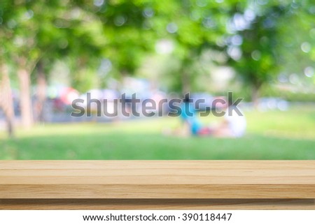 Empty wooden table over blurred park and people background, for product display montage