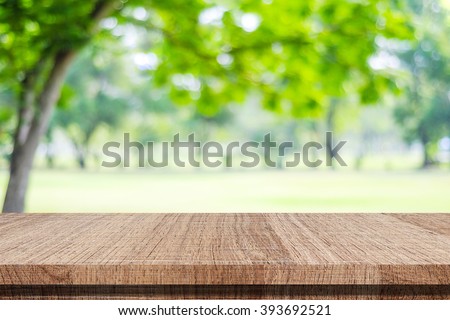Empty wooden table over blurred tree with bokeh background, for product display montage
