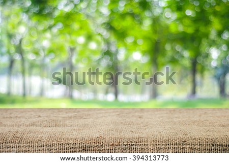 Empty table and sack tablecloth over blur tree with bokeh background, for product display montage