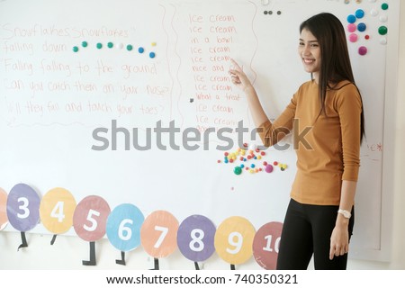 Young asian woman teacher teaching english kids in kindergarten classroom, preschool education concept