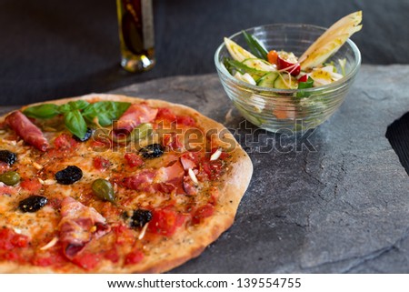 Home-made pizza with salad on stone slate