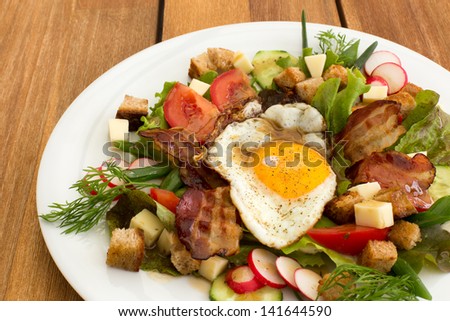 Peasant salad also called greek salad, village salad or country salad. Composed with lettuce, cucumber, onion, radish, fried egg and bacon, cheese, tomatoes, parsley and croutons.