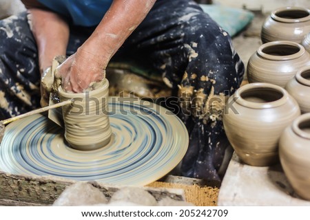 dirty hands making pottery in clay on wheel