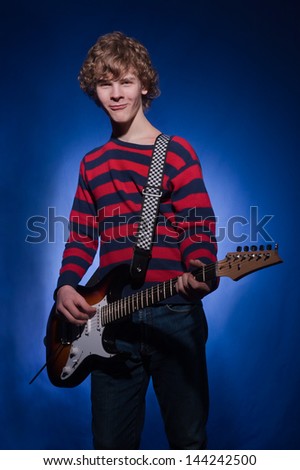 young guitarist plays the electric guitar Blues on a dark blue  background