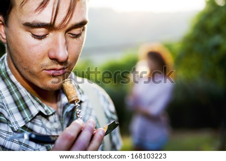 farmer sniffing wine cork to test the quality of the wine