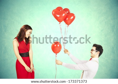 Man approaching woman giving her red heart shape balloons