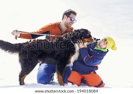 father, son and their dog having fun in the snow
