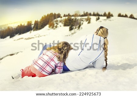 Mother hugs his daughter affectionately in the snow