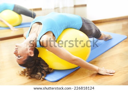 Woman making body exercises on a yellow ball