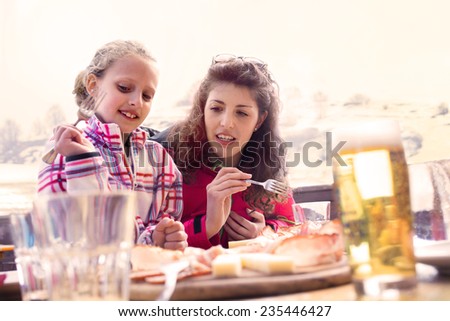 Mom and daughter have lunch in a chalet in the mountain