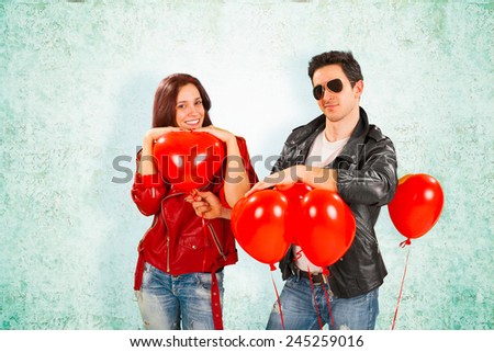 Romantic Handsome Rock Star Man, in Black Jacket and Shades, Giving Heart Balloons to Pretty Happy Girlfriend on Abstract Girlfriend.
