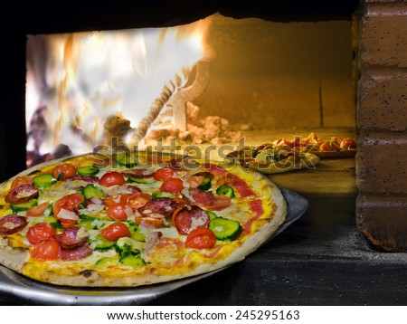 italian pizza coming out of a wood burning pizza oven