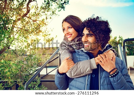 Portrait of Smiling Couple with Arms Around Each Other Outdoors and Looking to the Side