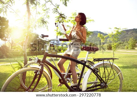 attractive woman on a bicycle resting under a tree