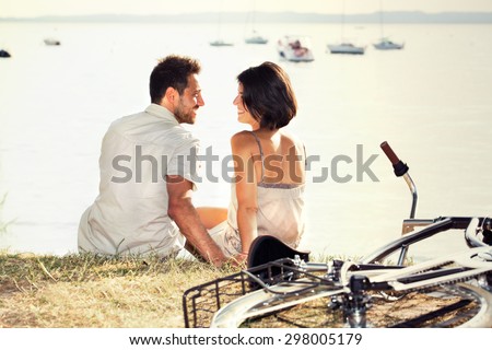 Couple with bicycle flirting in front of the lake