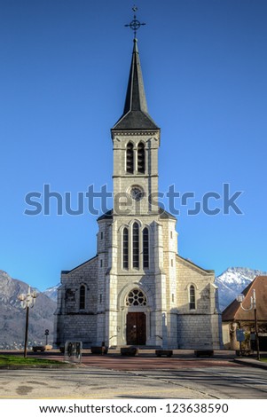 White church in French Alps town of Sevrier on Lake Annecy. This is taken with the Alps in the background on a clear blue sunny winter day. / Church in French Alps on Lake Annecy in Sevrier, France.