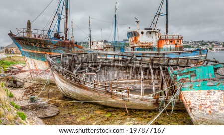 Camaret sur Mer\'s aged decaying wooden fishing fleet sits moored to the pier. The boats are weathered and rusty and falling apart. / Old Fishing Boats Decaying