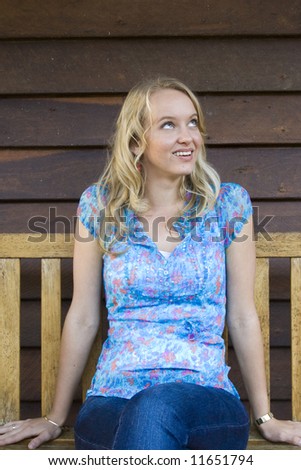 beautiful blond girl sitting on a bench seat smiling