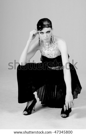 Attractive young woman squatting in a 1920s flapper style dress. Vertical shot.