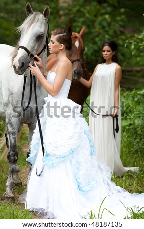 Beautiful young women leading horses in the country