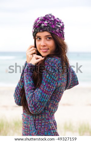 Beautiful young girl is cold and wearing a jumper and beanie after a day at the beach