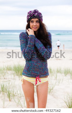 Beautiful young girl is cold and wearing a jumper and beanie after a day at the beach