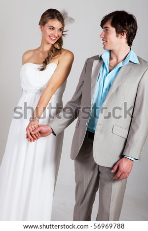 Attractive young and well dressed couple hold hands and smile at one another. Vertical shot.
