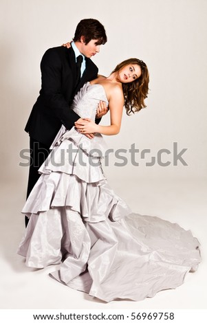 An attractive young couple in the midst of a dance move are dressed in formal attire. Vertical shot.