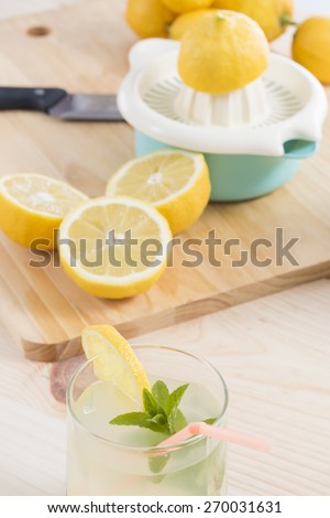 Glass and jug of natural fresh lemonade on wooden table with the squeezer and somes lemons