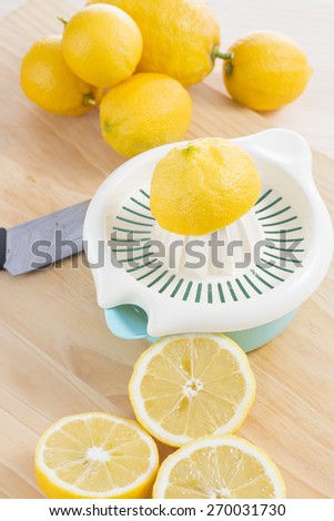 Squeezing fresh natural lemons with manual squeezer on wooden table. Making lemonade