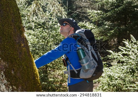 Hker man feeling the nature touching a tree trunk