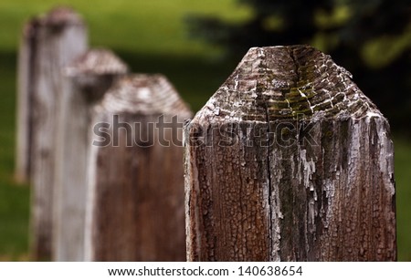Closeup of Weathered Fence Post With More Fenceposts in Distance