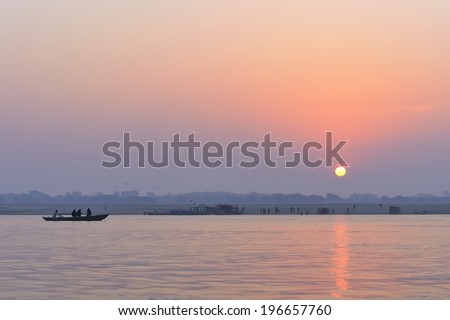 A group of people in a boat , contemplate the Sunrise over the river Ganges. Varanasi, India.