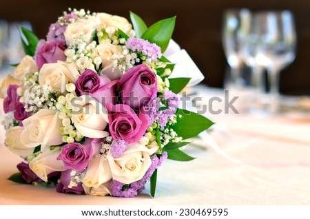 The bouquet of the newlyweds, rests on a table of guests at the banquet. The bouquet consists of white and pink roses.