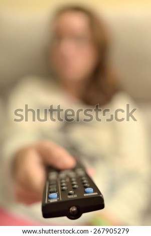 A woman pointing a remote control. The image has a minimum depth of field to make it more artistic.