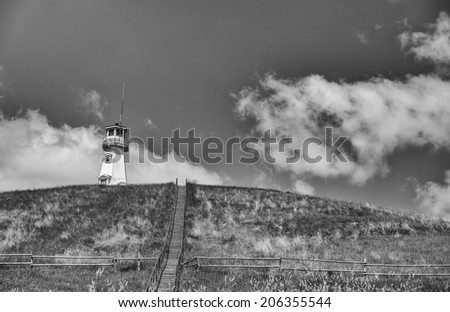 Stairs leading up a hill to a lighthouse in black and white