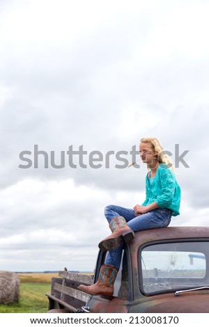 Young girl in western wear on hood of old truck