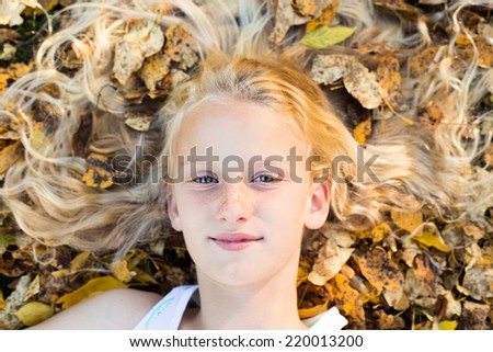 Face of young girl and autumn leaves