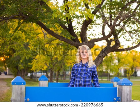 Young girl blue plaid shirt in front autumn tree