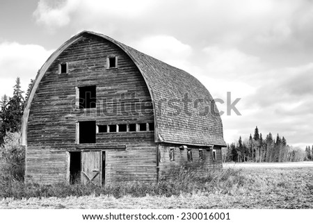 A weathered old barn with arched roof in black and white