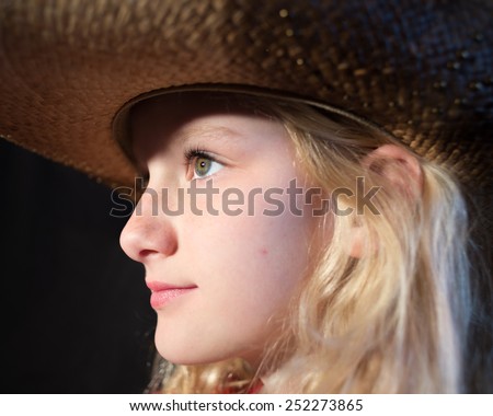 Side profile of young girls face wearing a cowboy hat
