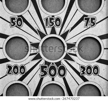 Circles cut out in a wood board with numbers under each one with a star burst in the centre in black and white